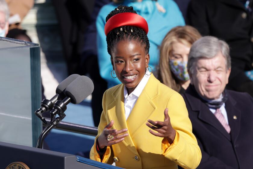 Amanda Gorman gesturing with her hands behind a podium