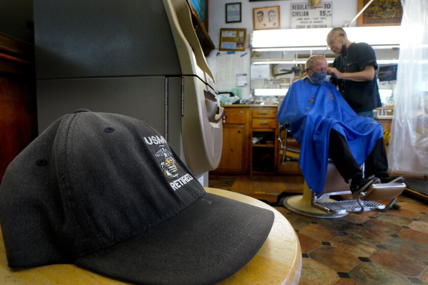 Oceanside, CA - August 18: On Wednesday morning, Aug. 18, 2021 at Esquire Barber Shop in Oceanside, CA., Johnny Gomez, 84 cuts the hair of Richard Mathys, a retired Marine. The sign posted above offers 1/3 discount to active military personnel. Gomez has been cutting hair at Esquire Barber Shop, since 1962. (Nelvin C. Cepeda / The San Diego Union-Tribune)