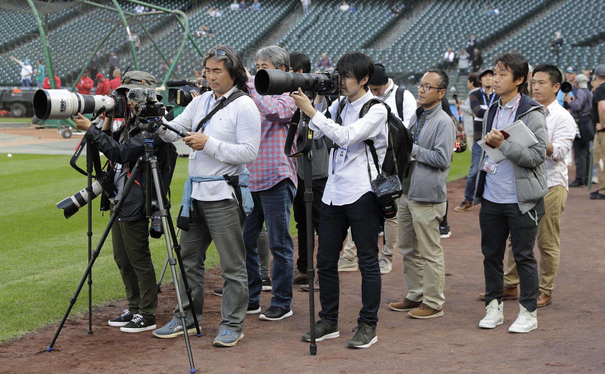 Members of the Japanese media watch the Angels' Shohei Ohtani throw in the outfield during practice in 2019.