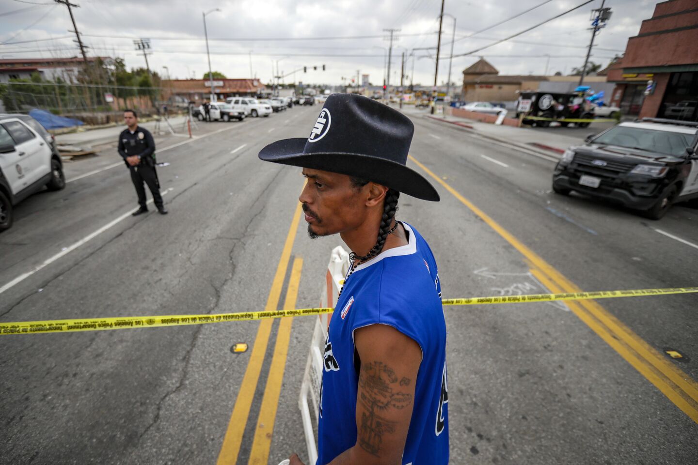 Herman Douglas, a.k.a. Cowboy, a business partner of Nipsey Hussle, stands behind police tape marking the crime scene as he pays his respect at a makeshift memorial for Hussle on April 2.