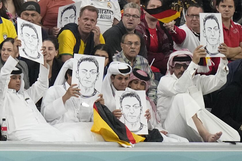 Espectadores qatarís sostienen imágenes del exjugador de la selección alemana Mesut Özil durante el encuentro entre Alemania y Espala el domingo 27 de noviembre del 2022 en el Estadio Al Bayt en aparente respuesta a la protesta de la selección alemana en su encuentro del miércoles. (AP Foto/Matthias Schrader)