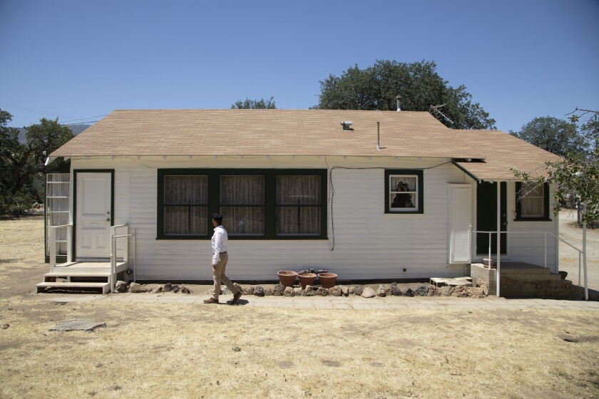 A man walks in front of a house.