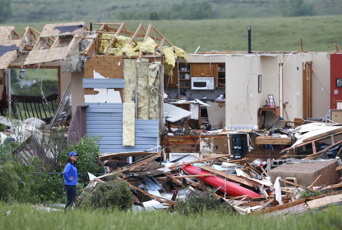 A woman surveys the damage around a home gutted by a tornado that struck Thursday near the town of Berthoud, Colo.