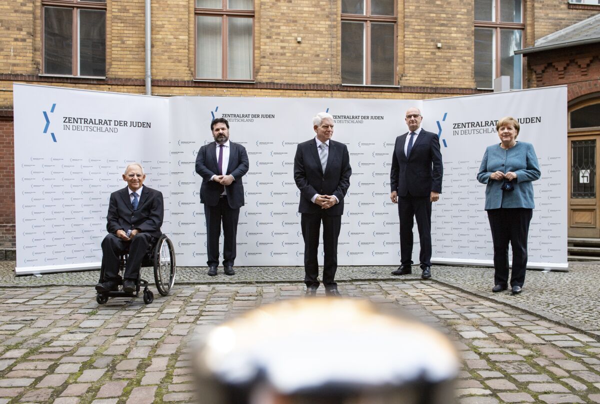 German Chancellor Angela Merkel, right, and Josef Schuster, center, President of the Central Council of Jews in Germany, joined Bundestag President Wolfgang Schaeuble, left, Gideon Joffe, second left, Chairman of the Jewish Community of Berlin, and Dietmar Woidke, second right, Minister President of Brandenburg and current President of the Bundesrat, in the courtyard of the New Synagogue for a group photo at the ceremony marking the 70th anniversary of the Central Council of Jews in Berlin, Germany, Tuesday, Sept. 15, 2020. The Central Council of Jews in Germany was founded on 19 July 1950 in Frankfurt am Main. (Bernd von Jutrczenka/Pool via AP)