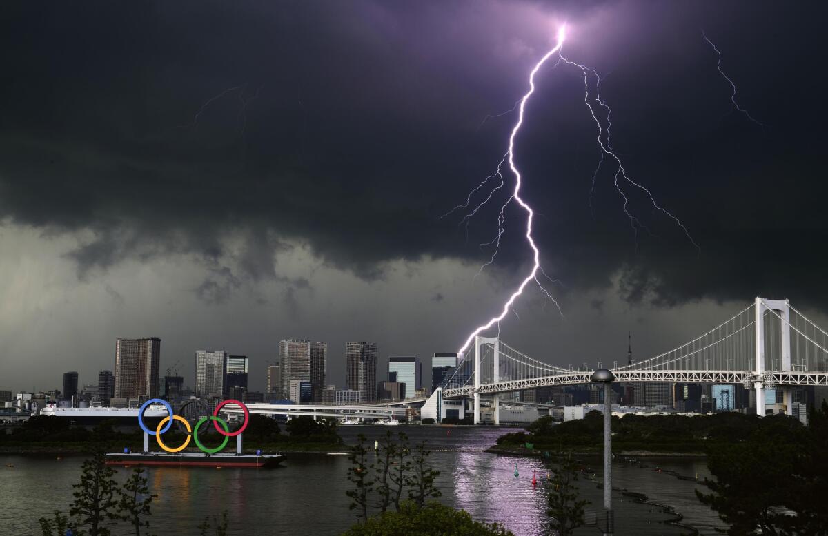 Lightning illuminates the sky over the Olympic rings and the Rainbow Bridge in Tokyo, Sunday, July 11, 2021. The opening ceremony of the postponed 2020 Summer Olympics is scheduled to be held in less than two weeks. (Kyodo News via AP)