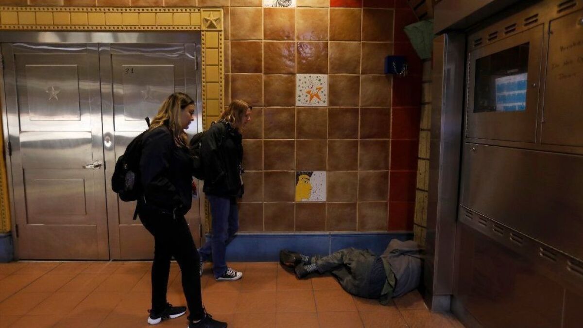Jennie Mauries, left, and Karen Barnes of the social services agency People Assisting the Homeless, talk with a man sleeping at the Hollywood/Vine subway station last January.