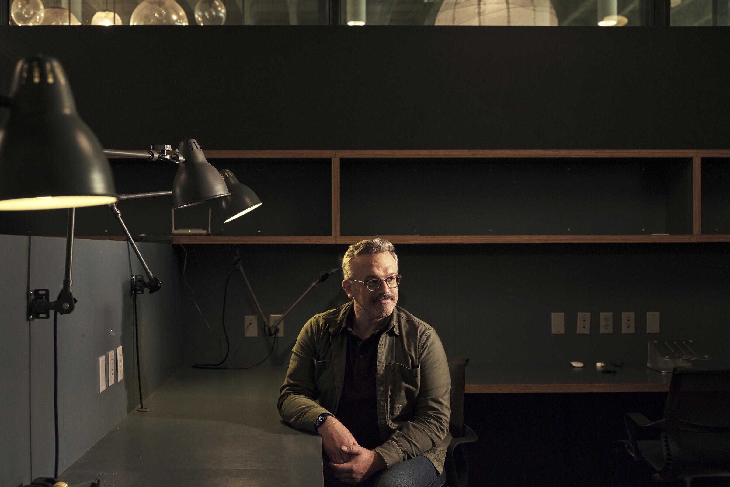 "Jury Duty" director Jake Szymanski sits at an industrial-looking workspace for a portrait.