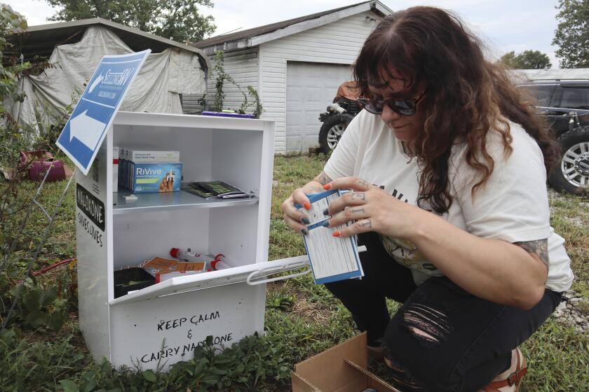 Tasha Withrow, a person in recovery and co-founder of harm reduction organization Project Mayday, refills a new naloxone distribution box in a residental neighborhood of Hurricane, W.Va. on Tuesday, Sept. 24, 2024. (AP Photo/Leah Willingham)