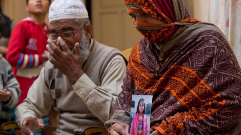 Nusrat Ameen holds a photo of her daughter, Zainab Ansari, who was raped and killed, as her husband sits beside her in Kasur, Pakistan.