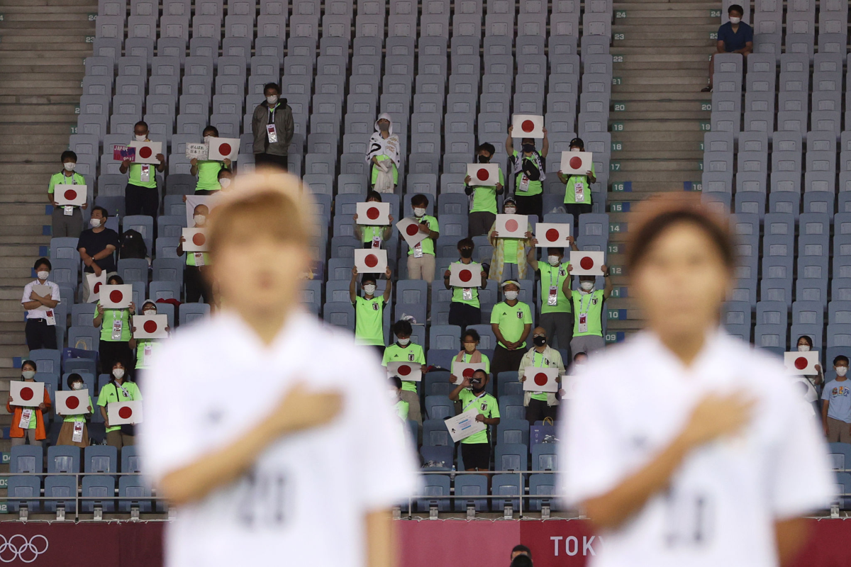 A few people in the stands hold up Japanese flag placards at the Tokyo Olympics.