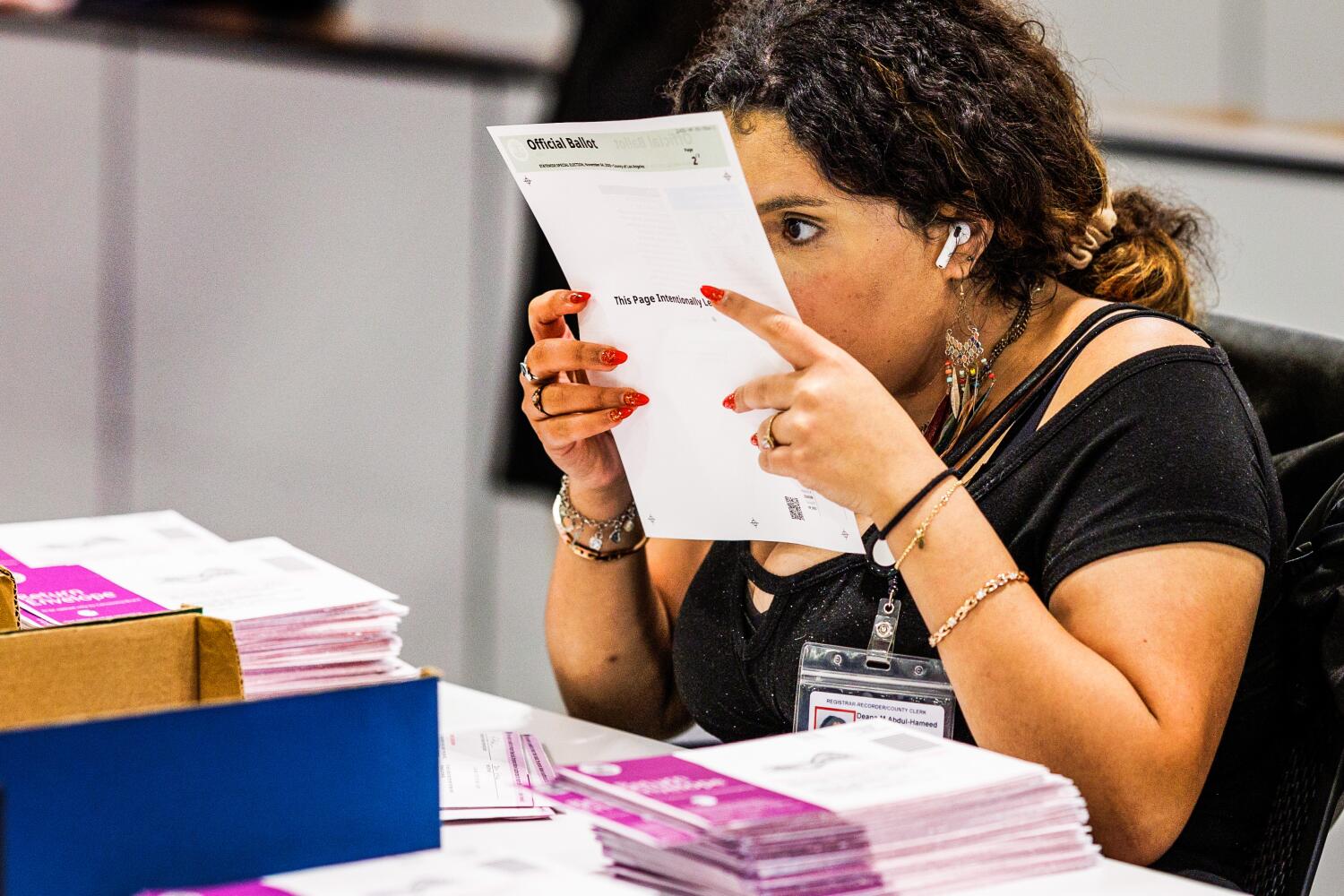 An election worker inspects a Vote by Mail ballot