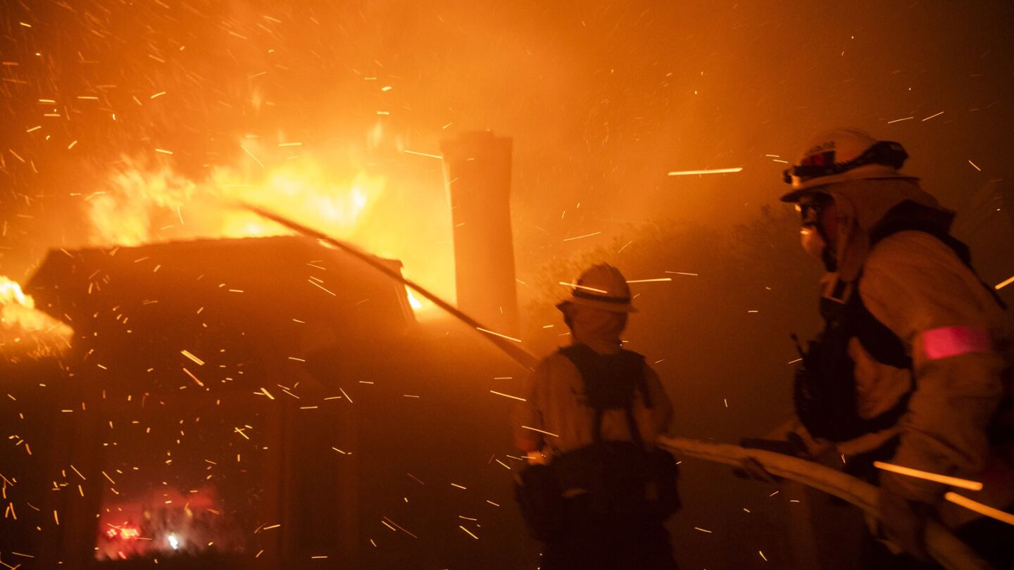 Firefighters try to keep embers from spreading to houses off Wembly Avenue and Lindero Canyon Road Thursday night as the Woolsey fire rages.