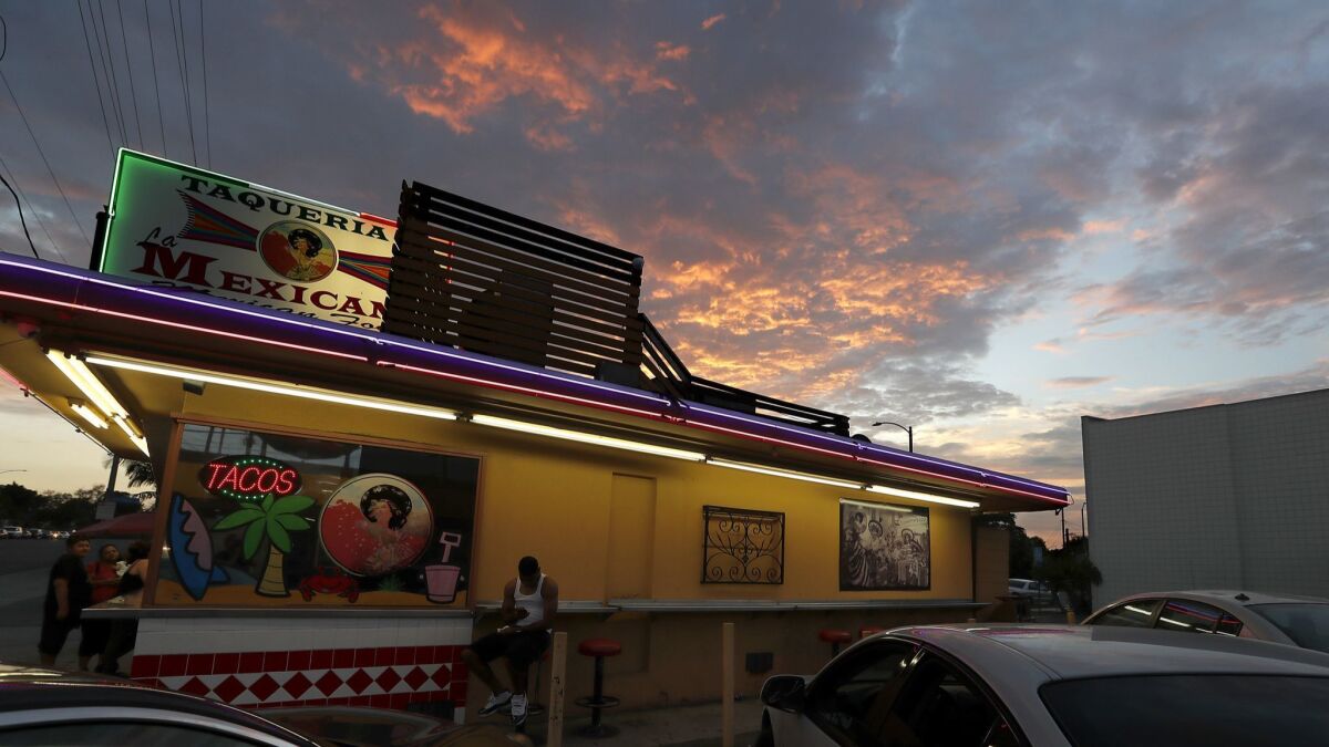 Fiery clouds drift over a taco stand in Long Beach, where monsoon-like weather will continue through Thursday before flowing out of the region.