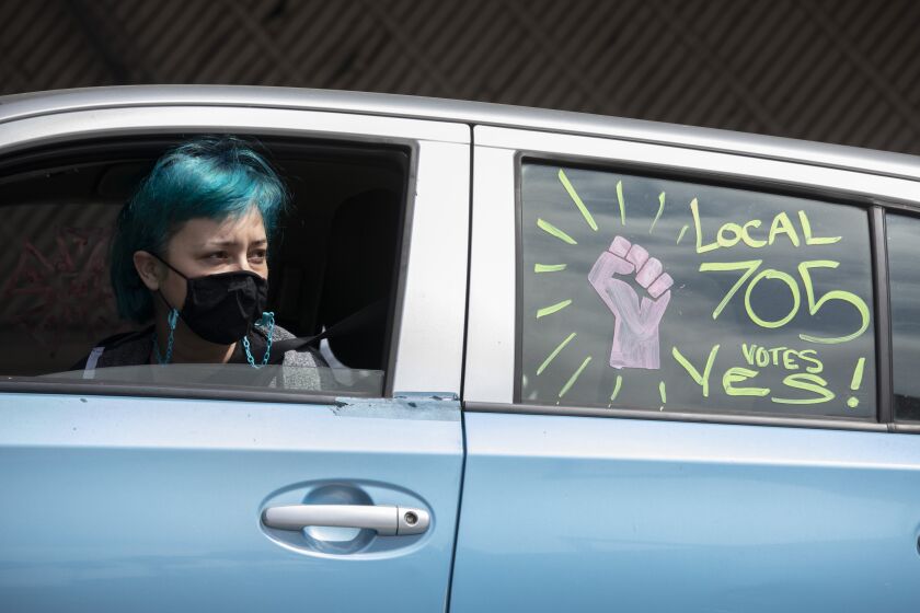 LOS ANGELES, CA - SEPTEMBER 26: Wendy Espinoza of Local 705, waits in her car as members draw pro-labor slogans during a rally at the Motion Picture Editors Guild IATSE Local 700 on Sunday, Sept. 26, 2021 in Los Angeles, CA. Up to 60,000 members of the International Alliance of Theatrical Stage Employees might go on strike in the coming weeks over issues of long working hours, unsafe conditions, less pay from streaming companies and demand for better benefits. (Myung J. Chun / Los Angeles Times)