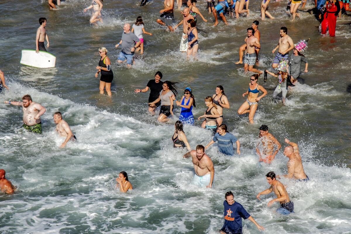 Surf City Splash participants run into the Pacific Ocean on New Year's Day in 2020.