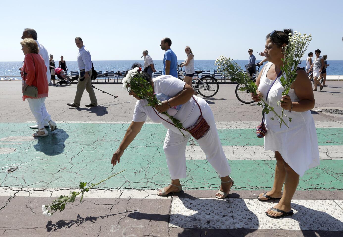 People place flowers on the Promenade des Anglais at the scene of Thursday's truck attack, prior to a minute of silence in Nice, southern France, Monday, July 18, 2016, to honor the victims of the Bastille Day attack.
