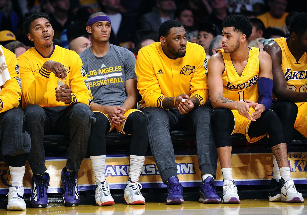 Lakers forward Nick Young, far left, and teamate D'Angelo Russell, right, sit on the bench apart from each other during a game against the Heat.