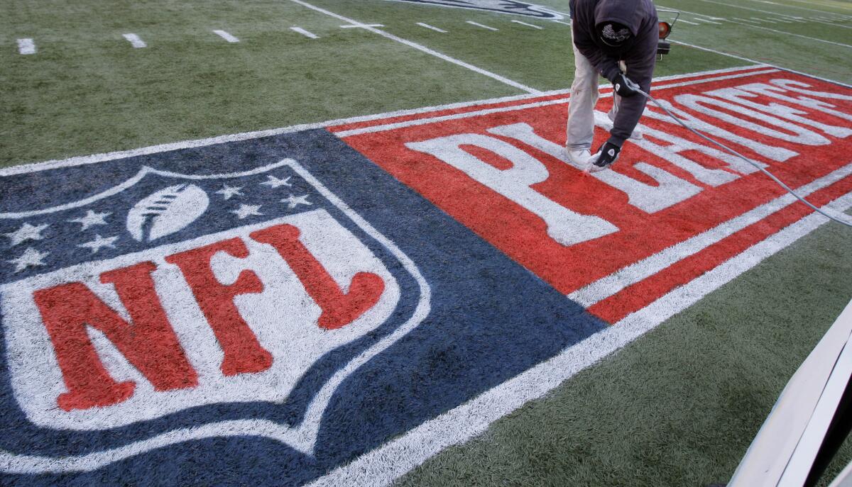 An NFL playoffs logo is painted onto a field.