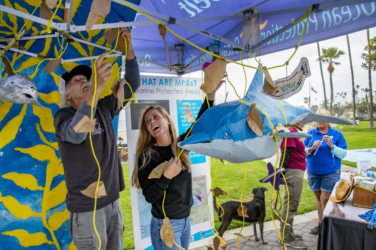 Anne Girtz and Mike Beanan set up a net and a papier-mache shark at the Laguna Bluebelt Coalition stand.