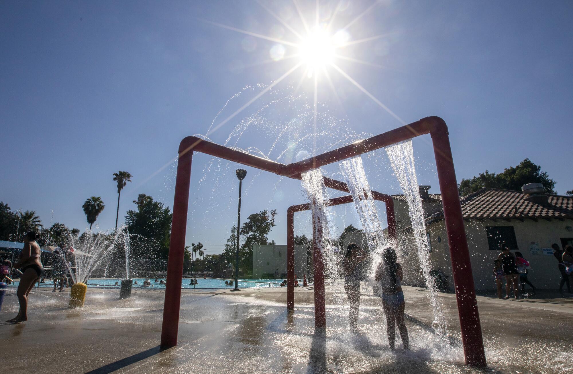 Children stand in falling water in a play area