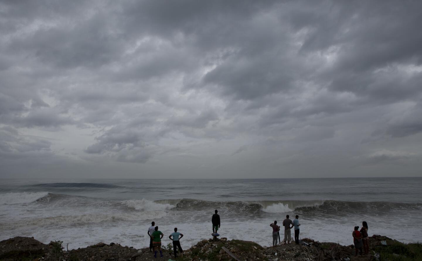 People stand on the coast watching the surf produced by Hurricane Matthew on the outskirts of Kingston, Jamaica, on Oct. 3, 2016.