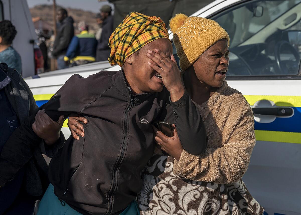 A woman weeps at the scene of an overnight bar shooting in Soweto, South Africa, Sunday July 10, 2022. A mass shooting at a tavern in Johannesburg's Soweto township has killed 15 people and left others in critical condition, according to police. Police say they are investigating reports that a group of men arrived in a minibus taxi and opened fire on some of the patrons at the bar shortly after midnight Sunday. (AP Photo/Shiraaz Mohamed)