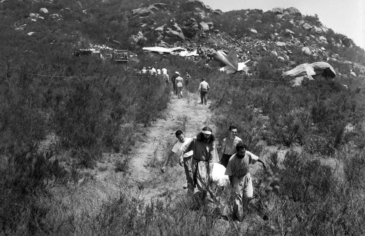 July 12, 1949: Krishna Venta, left, and Brother Paul of the Fountain of the World sect carry one of the plane crash victims to an ambulance.