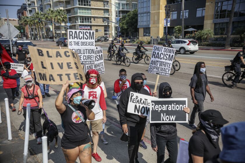 Demonstrators walk in downtown San Diego during the "March for Reparations to African People"which is a national day of political action coordinated by the Uhuru Solidarity Movement on Saturday, October 17, 2020.(Photo by Sandy Huffaker for The San Diego Union-Tribune)