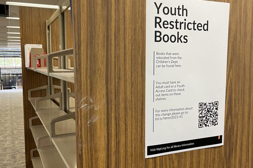 A mostly empty shelf of books with a sign noting "Youth restricted books"