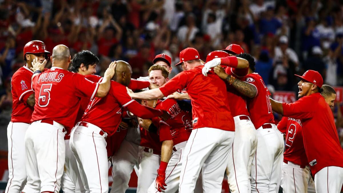 Angels second baseman Ian Kinsler (3) was at the center of the celebration after Kinsler's hit allowed the Angels shortstop David Fletcher (6) to score the game winning run.