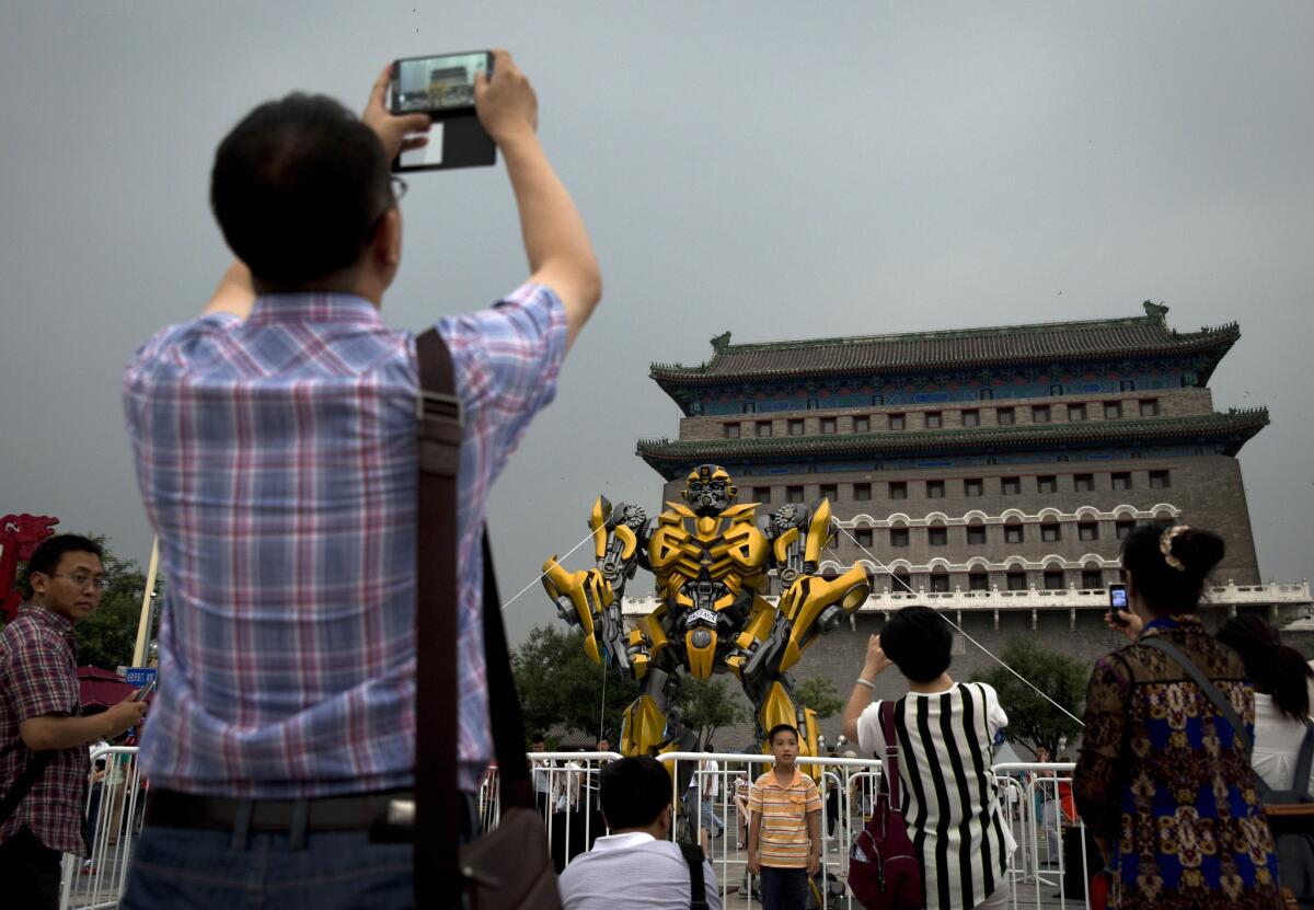 Visitors to Beijing's Pangu Plaza take photos Saturday of a replica of the Transformer Bumblebee on display as part of a promotion of the movie "Transformers: Age of Extinction."