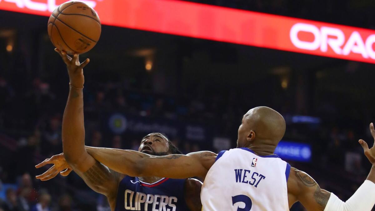 Clippers' DeAndre Jordan puts up a shot despite getting hit on the arm by Golden State's David West in the first half.