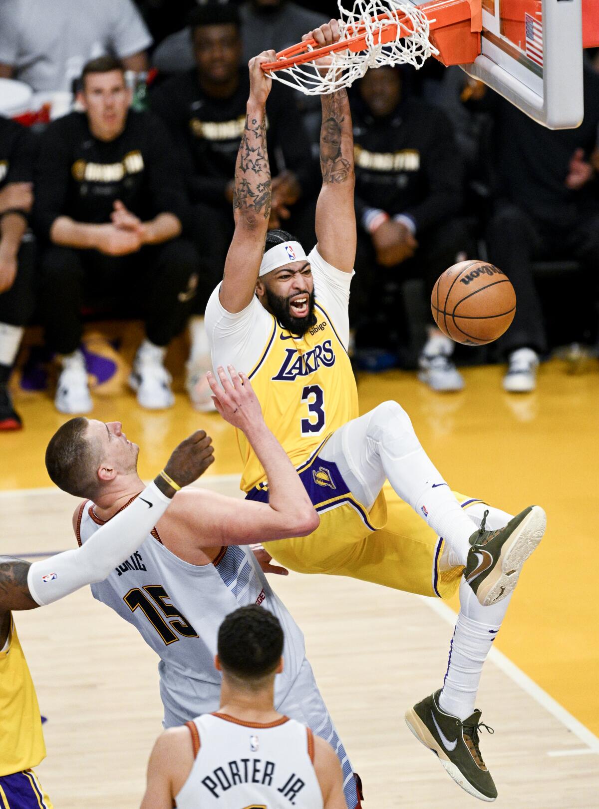 Lakers forward Anthony Davis, right, reacts after a dunk in front of Nuggets center Nikola Jokic.