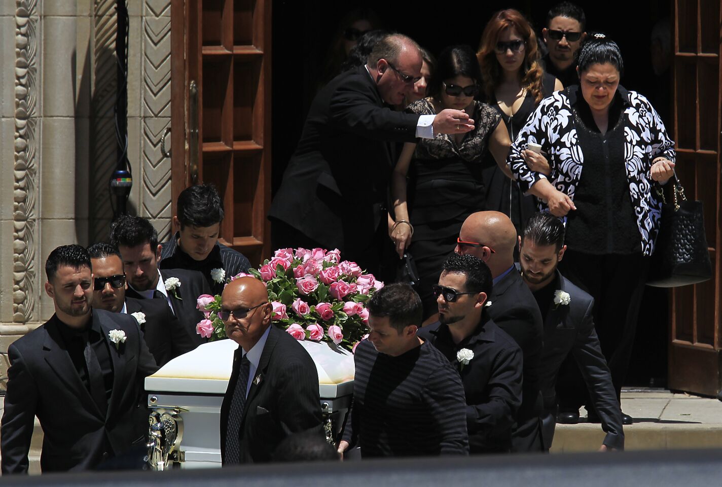 Pallbearers carry the casket of Marcela Franco as family member are escorted out following a funeral mass for Marcela and Carlos Franco at Saint Monica's Catholic Church.