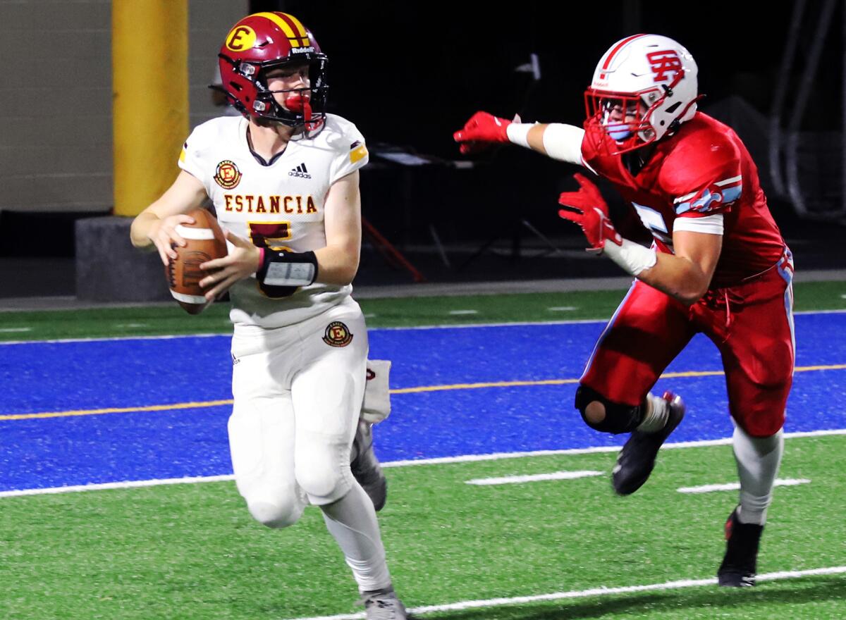Estancia quarterback Riley Witte, left, scans the field as Santa Ana's Michael Hughes rushes in a game at the Santa Ana Bowl.