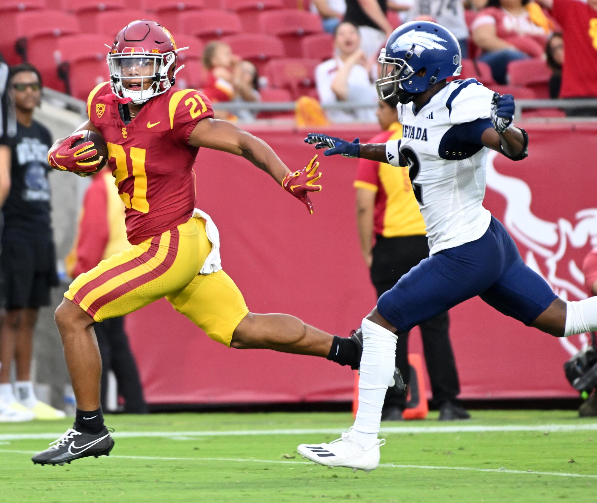 A USC player runs toward the end zone as a Nevada player chases