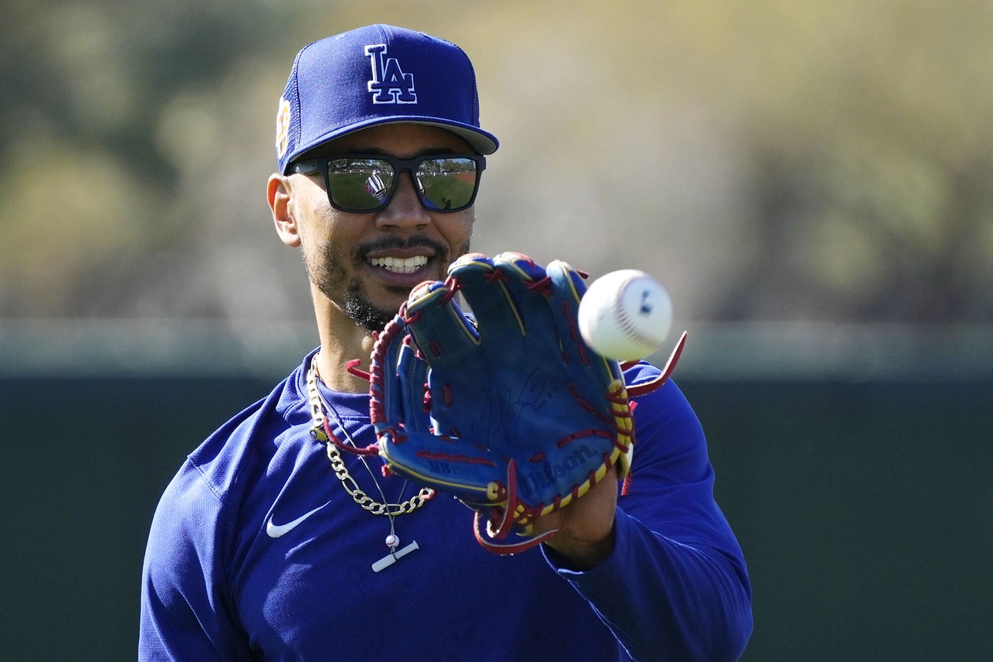 Los Angeles Dodgers' Mookie Betts reaches to catch a baseball while warming up.
