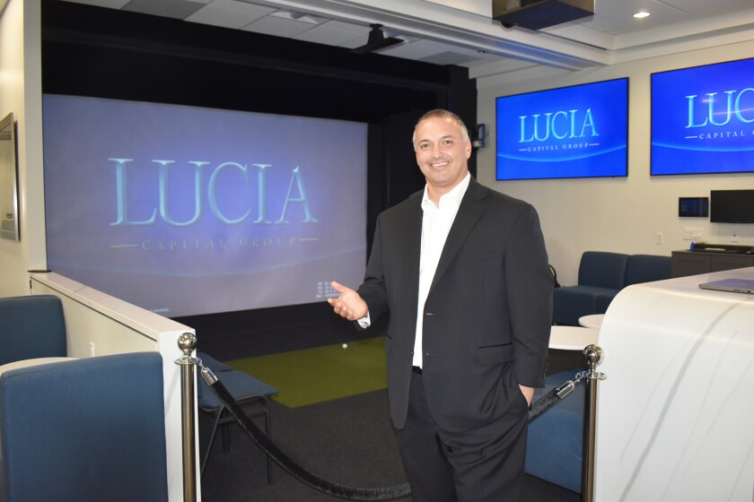 Raymond J. Lucia Jr. in front of the presentation room's 16-foot by 10-foot screen that can be turned into a golf simulator.