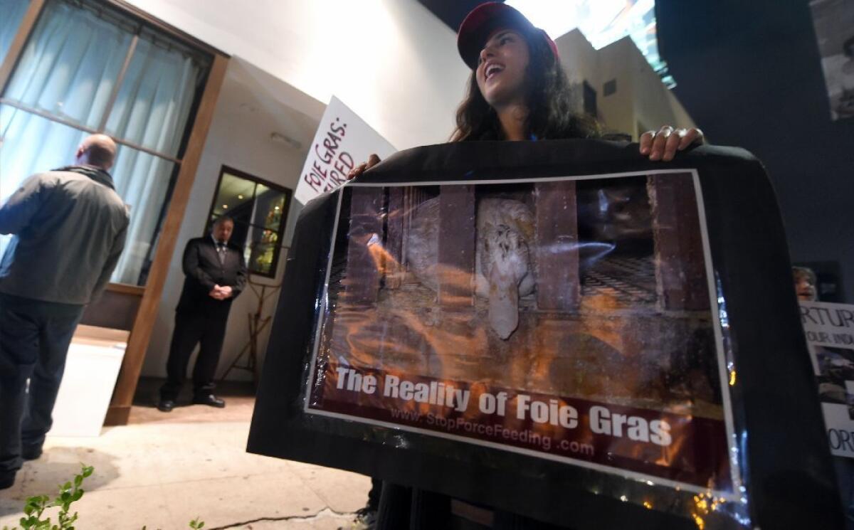 Activists hold placards and shout slogans while gathered outside a restaurant serving foie gras in Beverly Hills.
