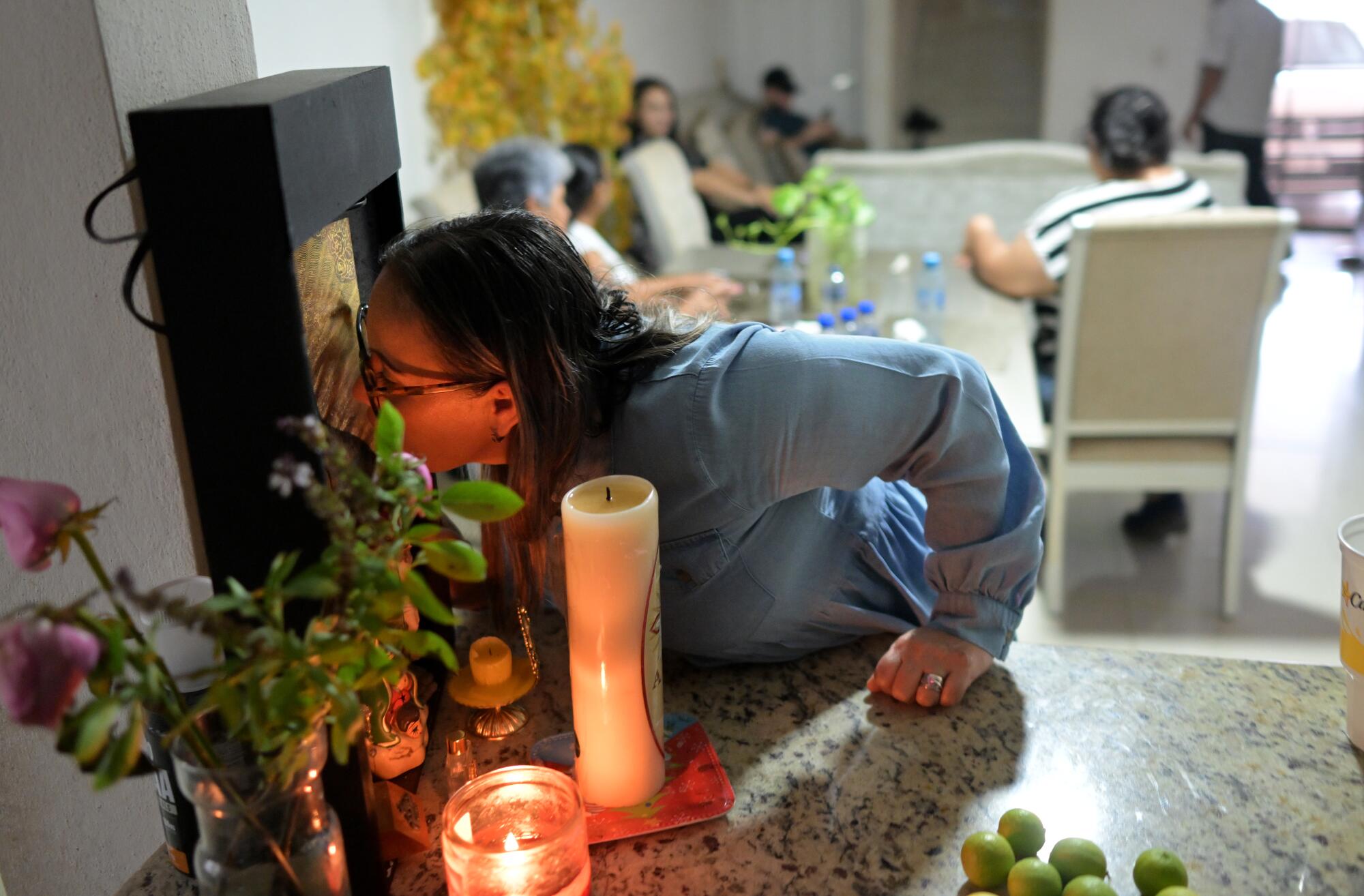 Juana Isabel Acosta kisses the Virgin Mary at the family home in Culiacan, Mexico while her son Julio Urías pitches on TV