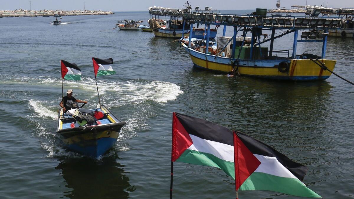 Palestinian fishermen fly national flags at the Gaza City seaport on July 17, 2018, after the fishing zone enforced by Israel off the Gaza Strip was reduced, part of Israel's tightening of its blockade of the Gaza Strip.