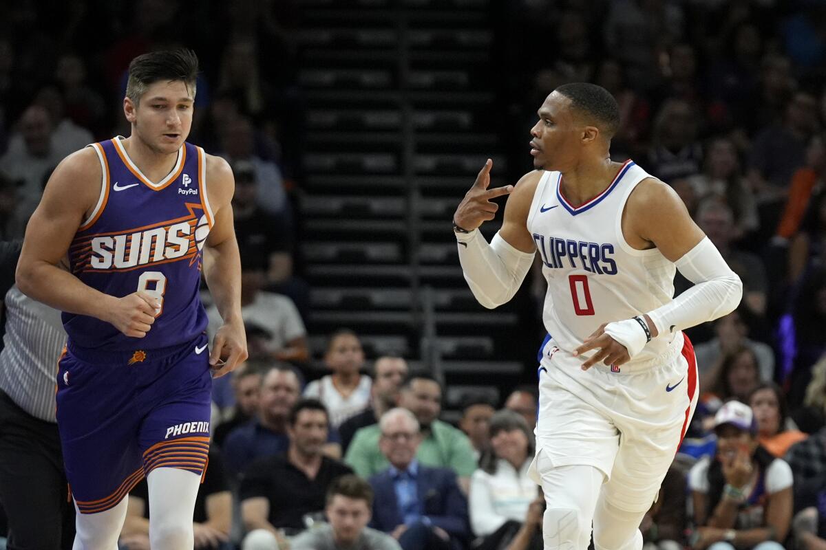 Russell Westbrook celebrates his three-pointer as he runs past Suns guard Grayson Allen in the first half.