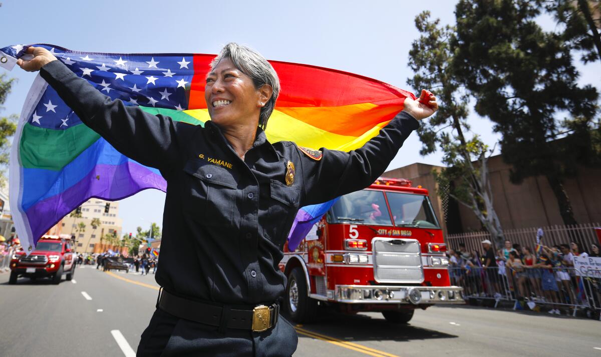 San Diego Fire-Rescue Department Battalion Chief Grace Yamane carries a gay pride rainbow American flag