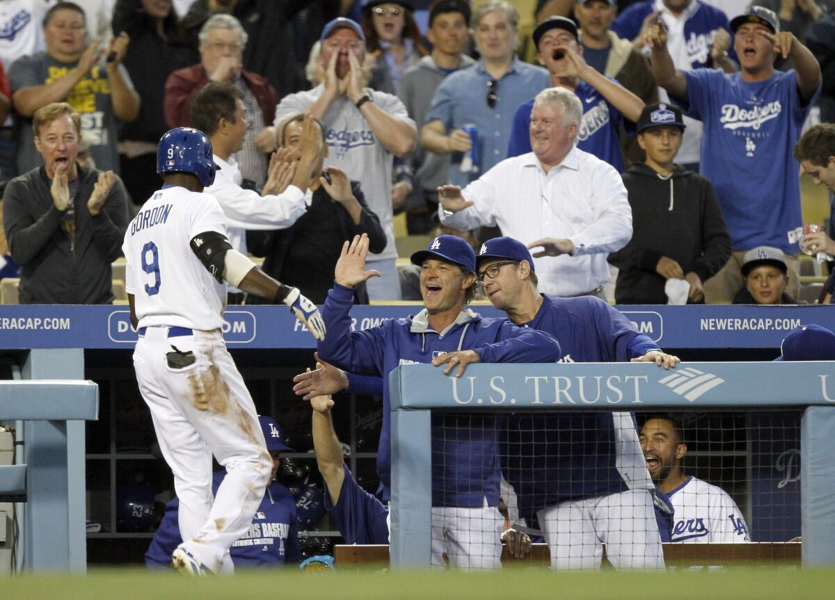 Dee Gordon is congratulated by Dodgers Manager Don Mattingly, center, and bench coach Tim Wallach, right, after scoring on a triple and an error by Colorado's Charlie Blackmon in the third inning.