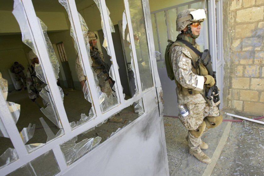 FILE—This file photo from Aug. 6, 2005, shows U.S. Marine Staff Sgt. Brian Hamilton of Columbus, Ohio, from Lima Company of the 3rd Battalion, 25th Regiment as he exits after searching a school, in Parwana, near Haditha, Iraq. Days before, a nearby roadside bomb killed 14 Marines, many from this platoon, and a civilian interpreter on August 3, 2005. Some survivors and families of those killed had planned a 15-year reunion this weekend, but it had to be canceled amid restrictions for the COVID-19 pandemic. (AP Photo/Jacob Silberberg, File)
