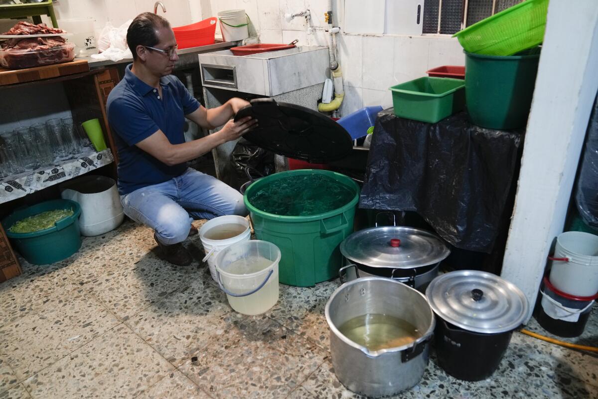 El propietario de un restaurante, Luis Alirio Soler, muestra cubos de agua 