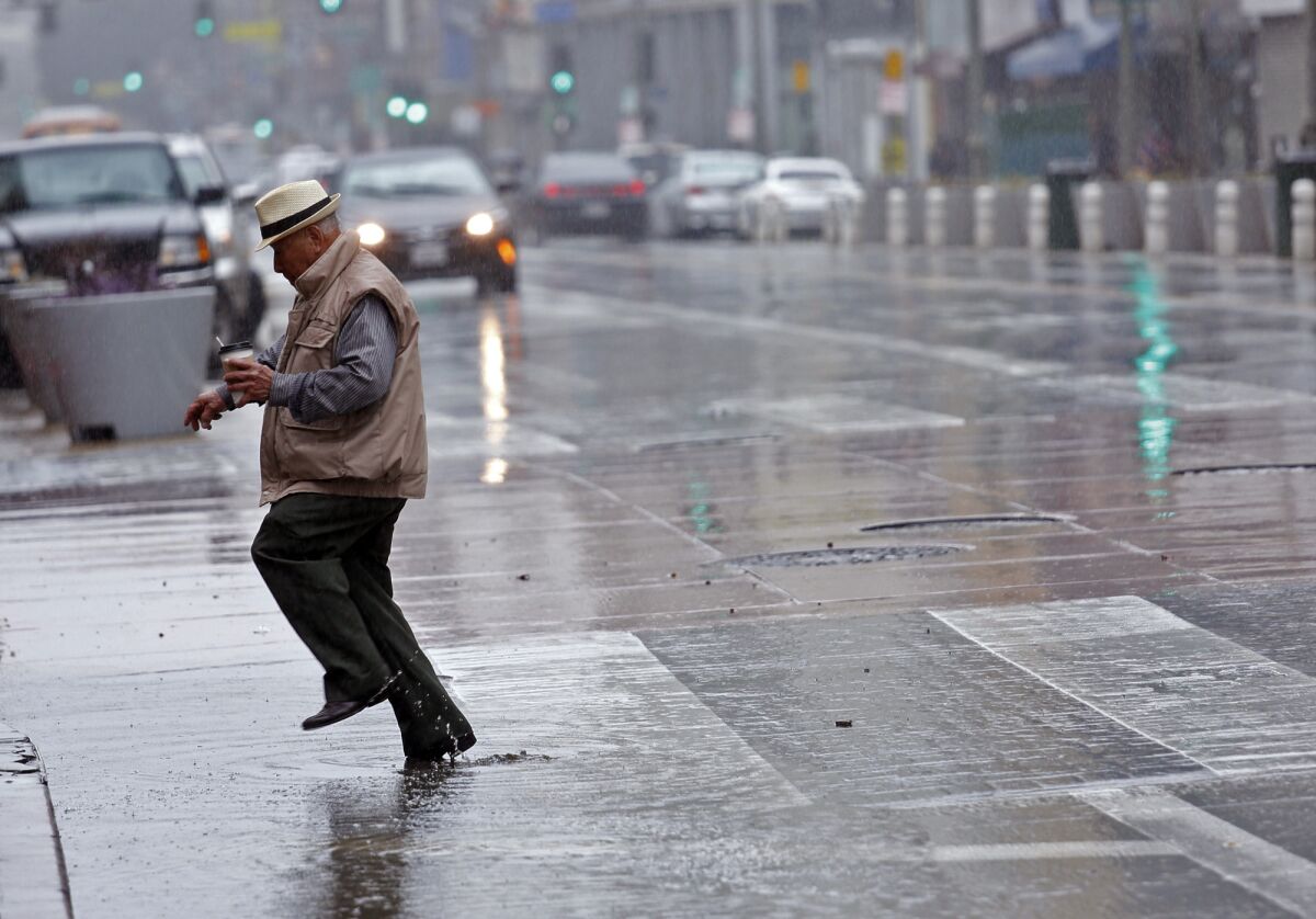 A man jumps a puddle along Broadway in downtown Los Angeles on Sunday.