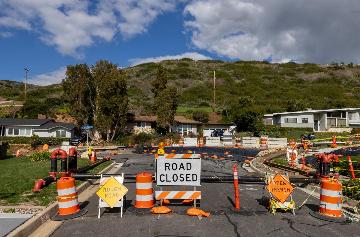 A road damaged by land movement is blocked with signage. 