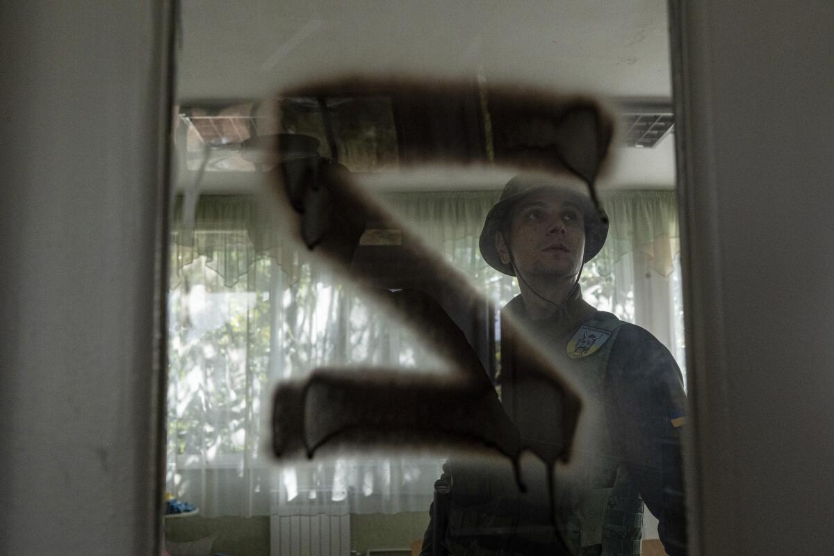 Ukrainian serviceman inside schoolroom with "Z" painted on door window