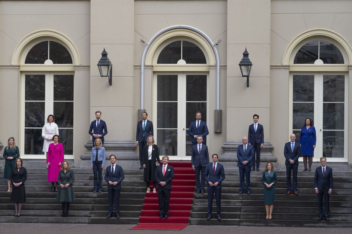 Dutch King Willem-Alexander, center, and Prime Minister Mark Rutte, center left, pose with other ministers of the new the government at Royal Palace Noordeinde in The Hague, Netherlands, Monday, Jan. 10, 2022, after been sworn in by the King as the new ruling coalition amid a nationwide coronavirus lockdown and policy challenges ranging from climate change to housing shortages to the future of agriculture. (AP Photo/Peter Dejong)